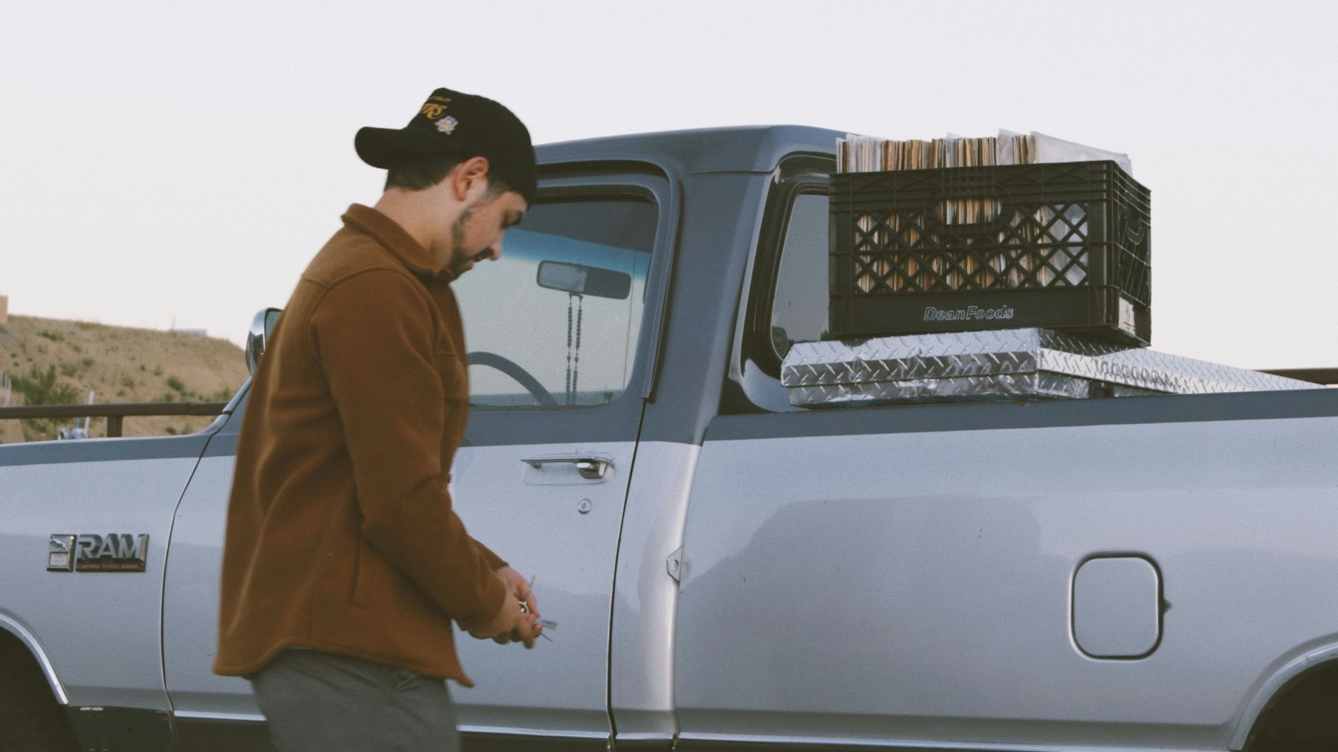 man in brown jacket standing in front of white crew cab pickup truck