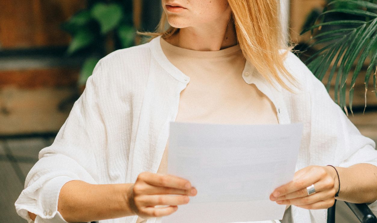 Focused woman with glasses holding documents in a modern workspace, looking thoughtful