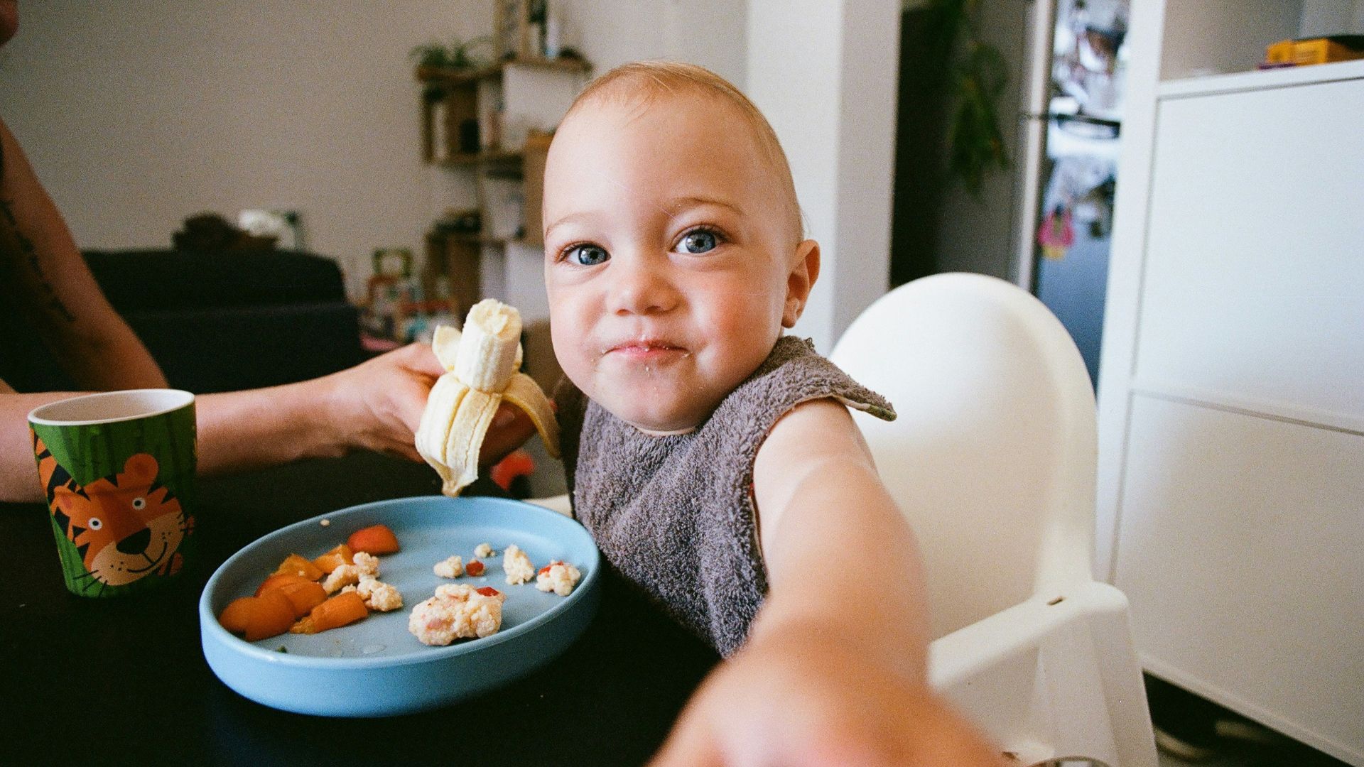 a baby sitting at a table with a plate of food