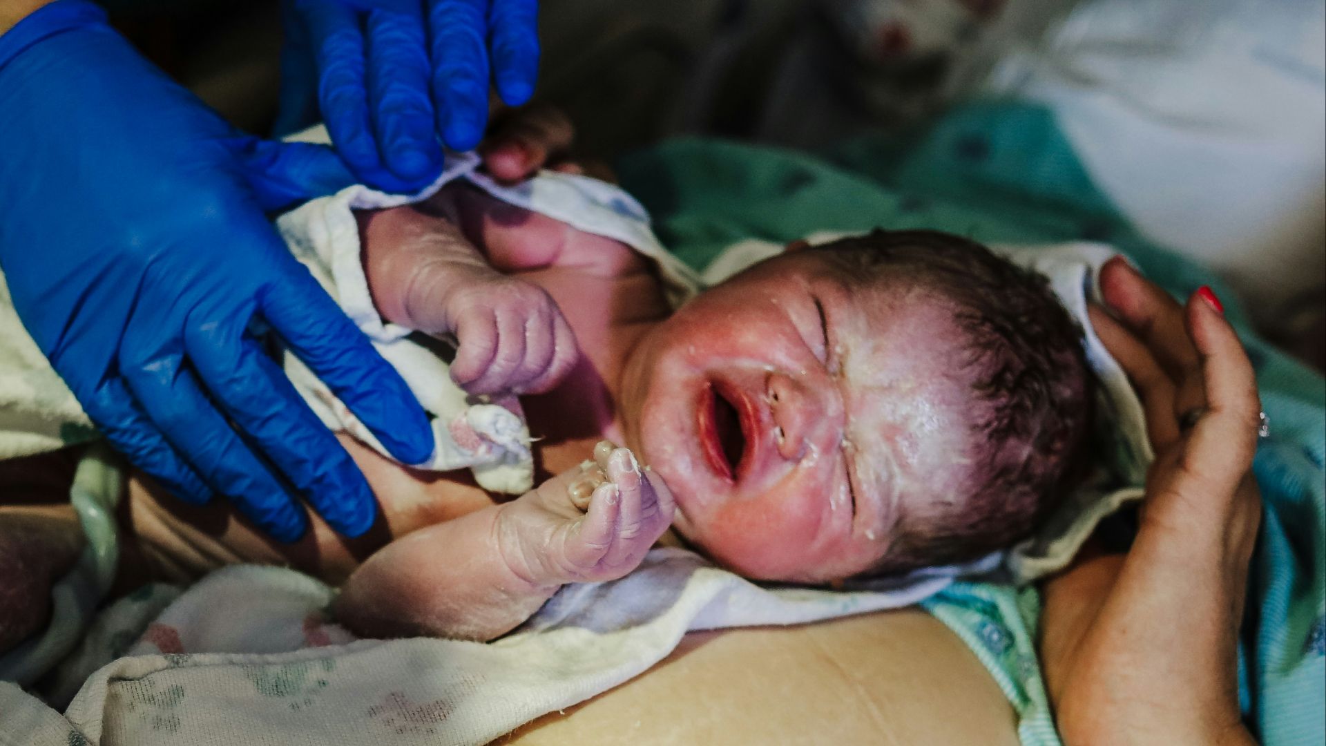 a person in blue gloves is holding a baby