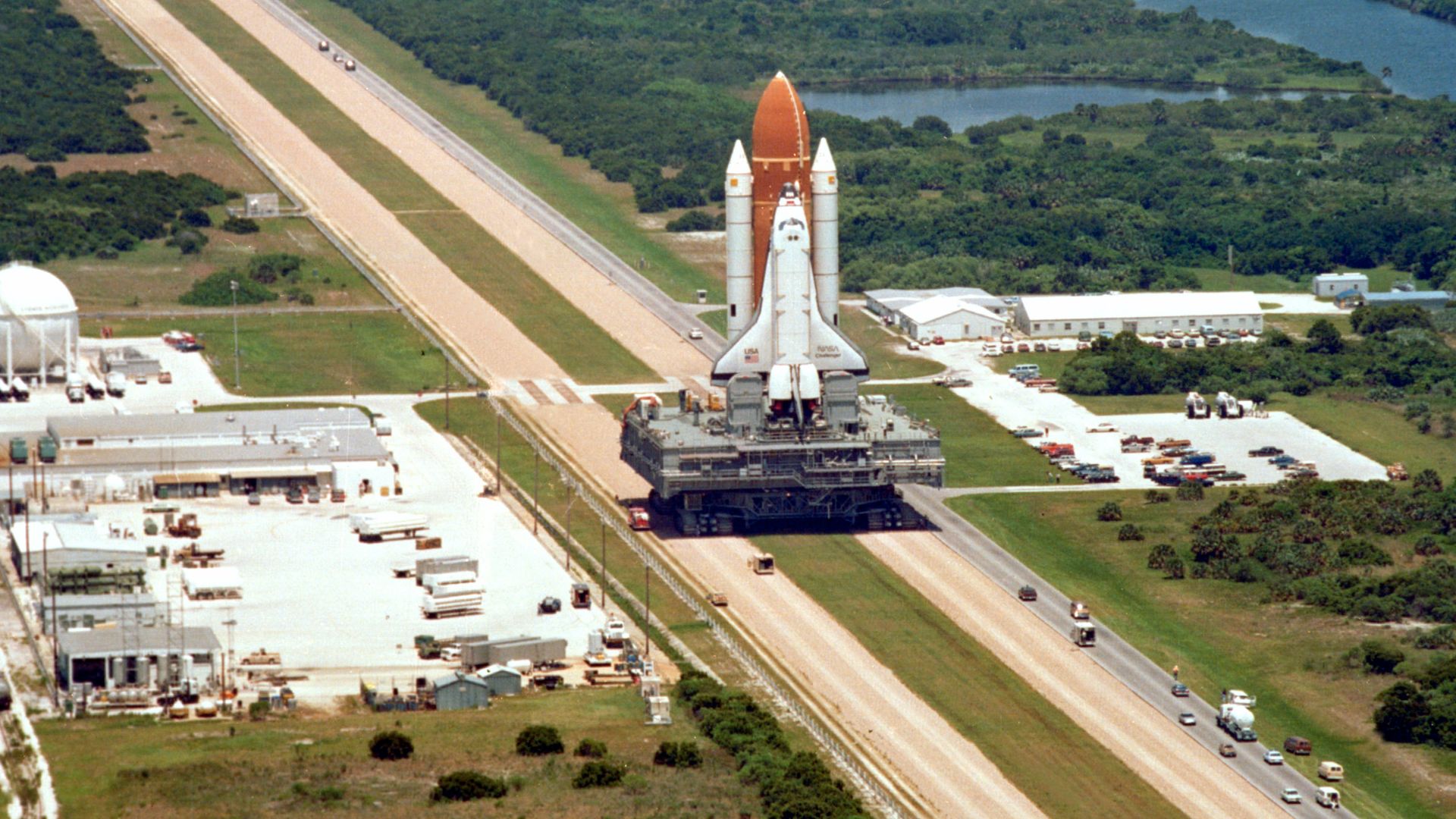 Space Shuttle Challenger is carried by a Crawler-transporter on the way to its launch pad, prior to its final flight before being destroyed in the Space Shuttle Challenger disaster.