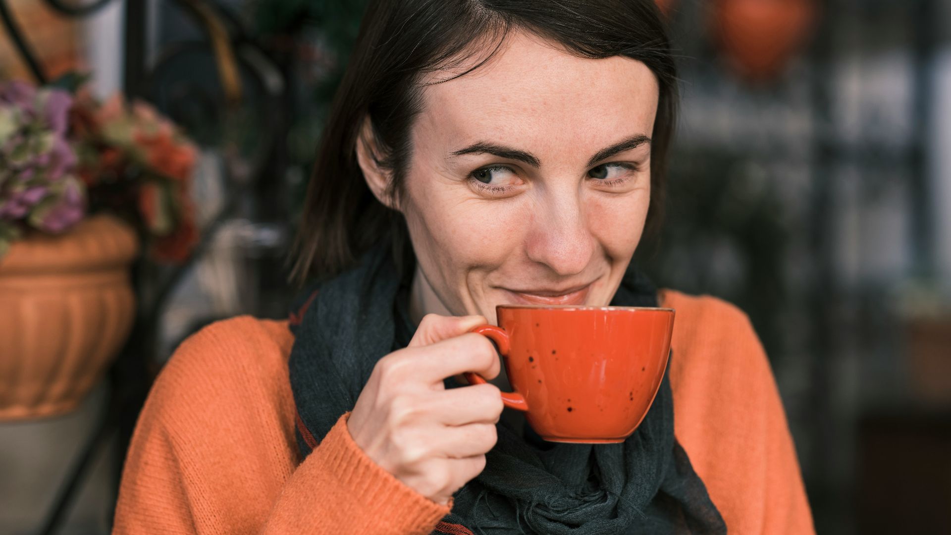 a woman holding a cup of coffee and smiling
