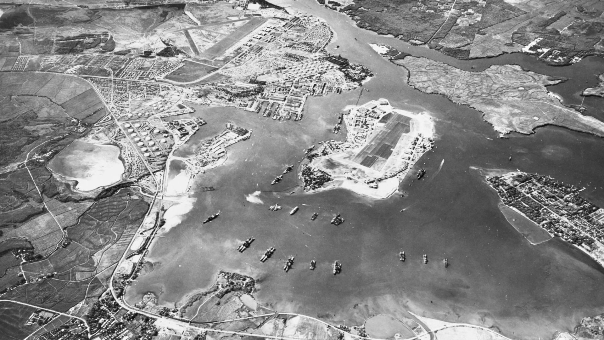 Aerial view of the U.S. Naval Operating Base, Pearl Harbor, Oahu, Hawaii (USA), looking southwest on 30 October 1941. Ford Island Naval Air Station is in the center, with the Pearl Harbor Navy Yard just beyond it, across the channel. The airfield in the u