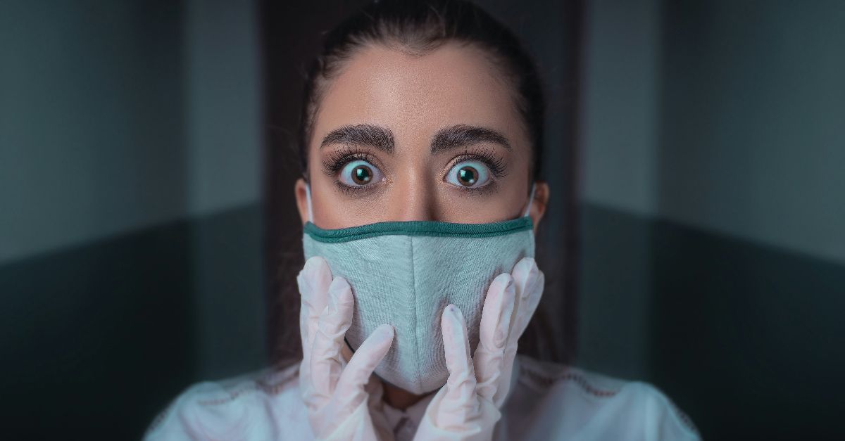 woman in white long sleeve shirt covering her face with blue and black face mask