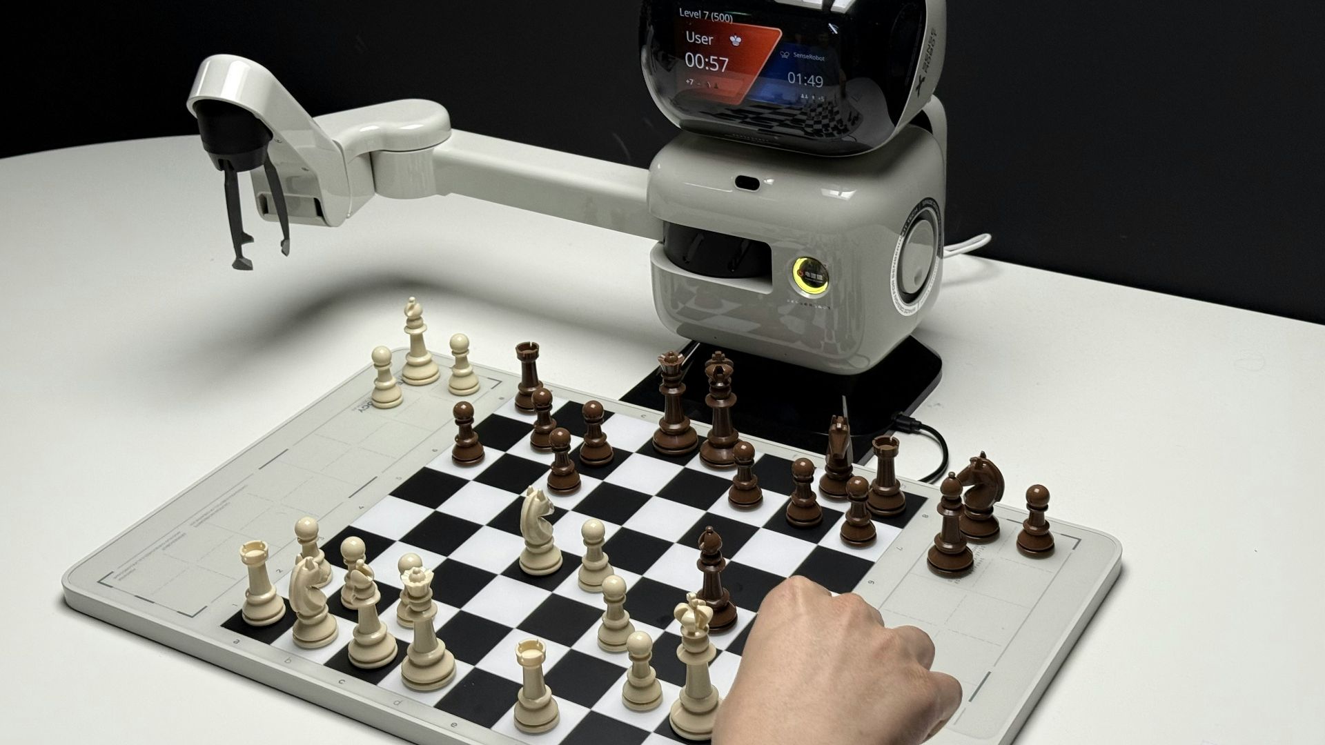 Robot arm playing chess against a human opponent.