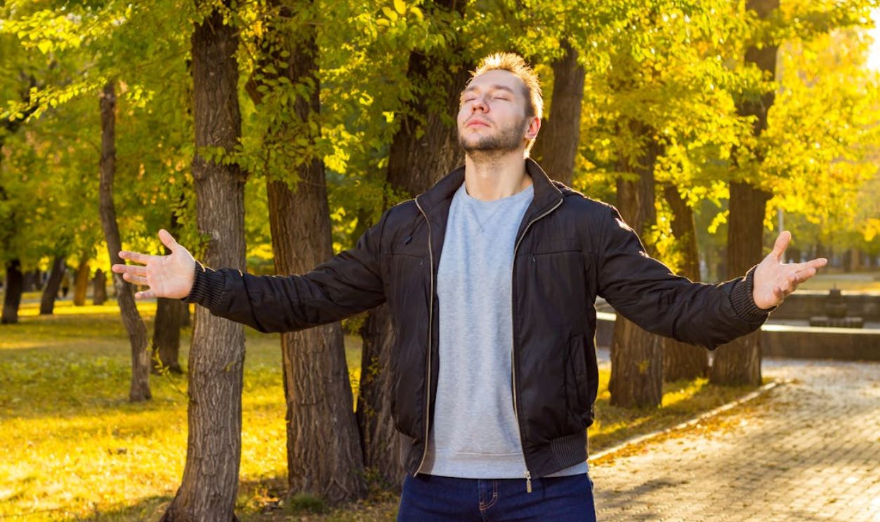 Caucasian man with eyes closed embracing nature in an autumn park