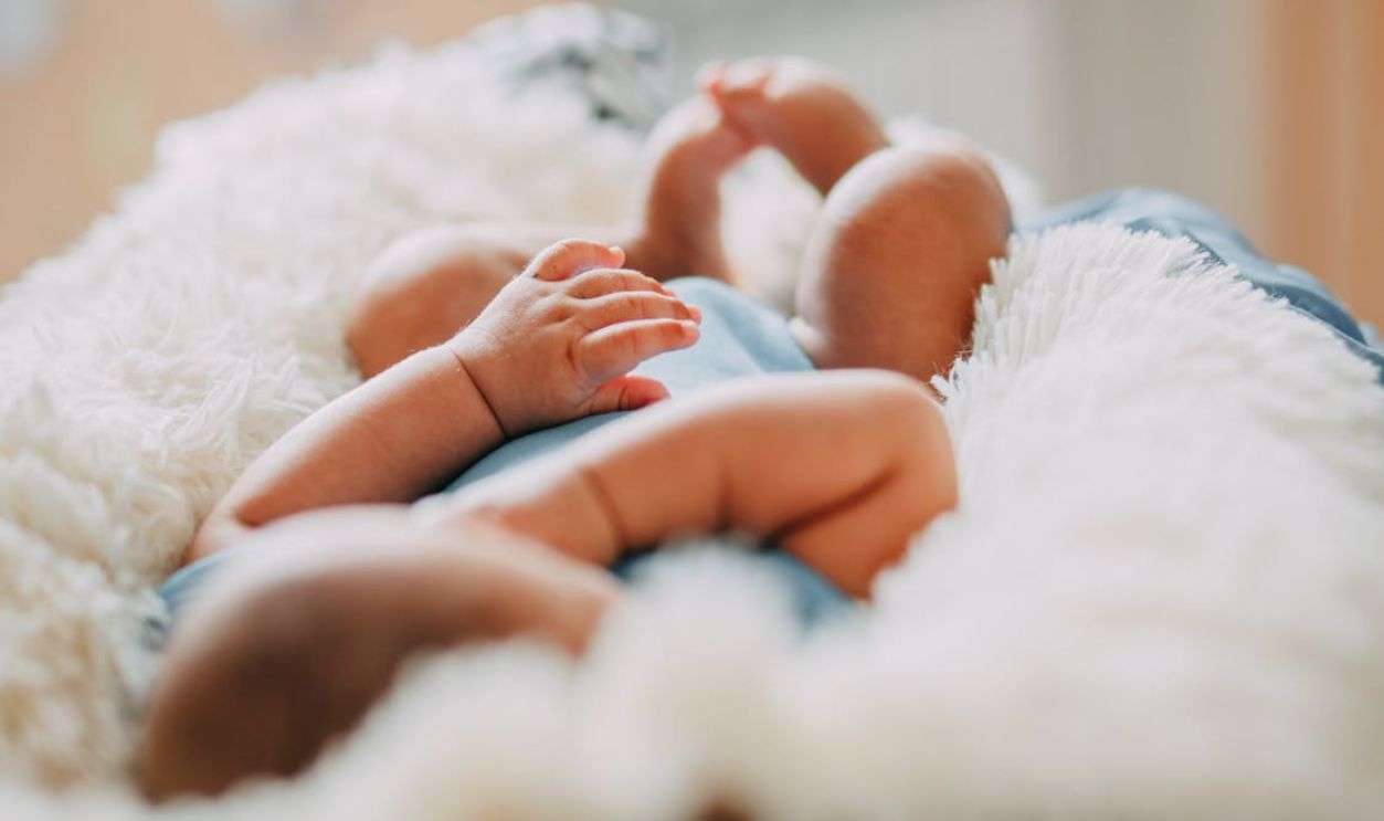 A serene close-up of a sleeping newborn lying on a fluffy blanket indoors.