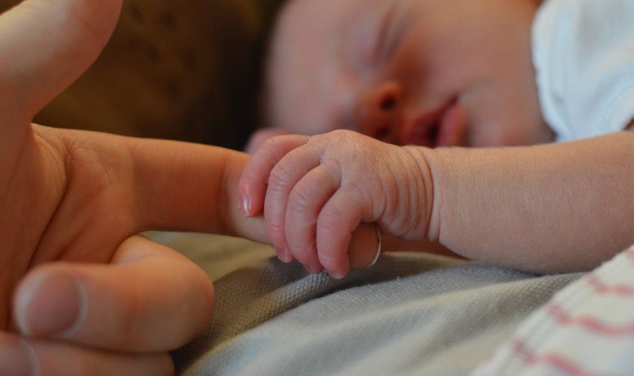 A heartwarming close-up of a newborn baby gently holding an adult's finger, symbolizing love and connection.