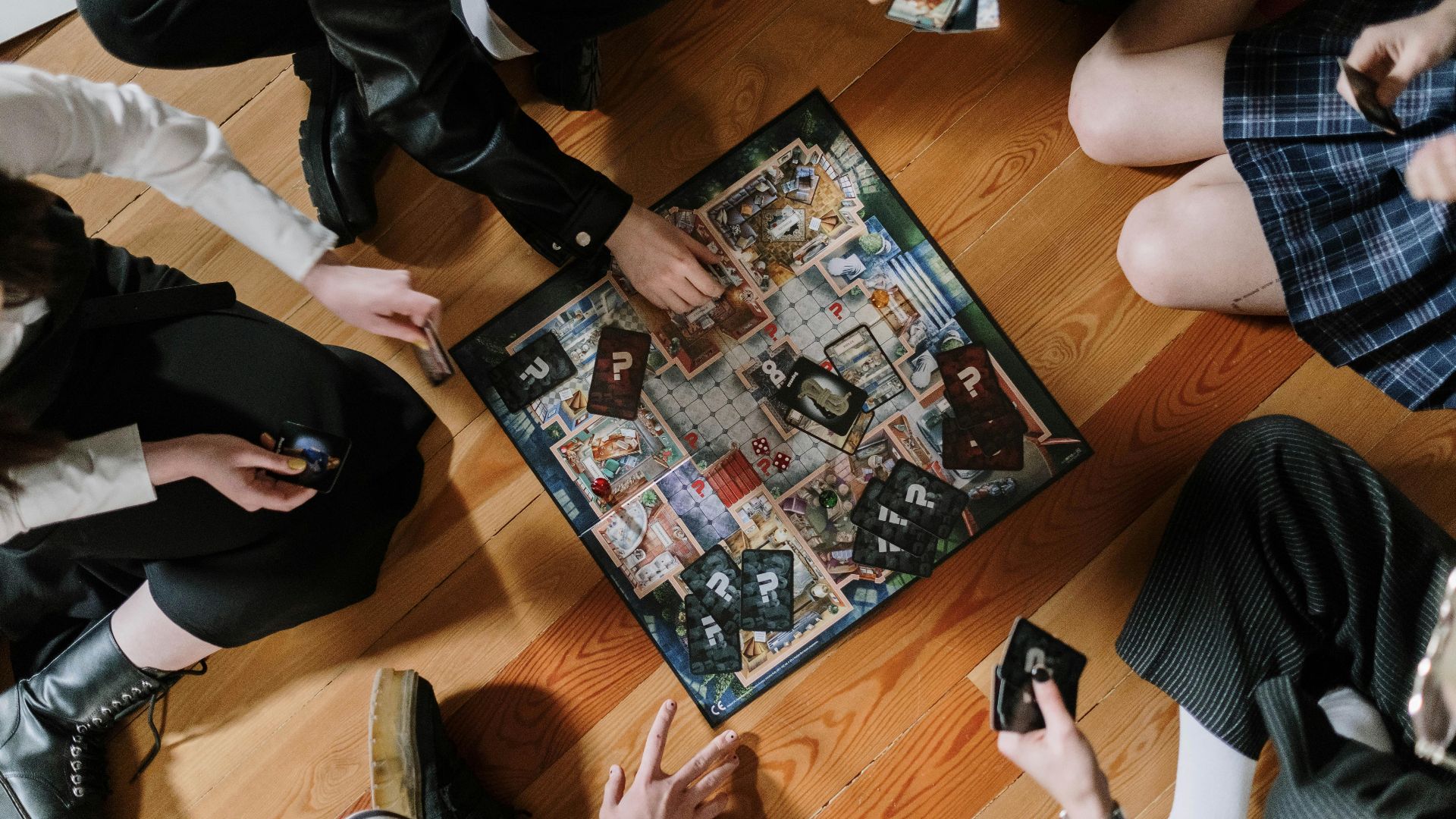Aerial view of friends enjoying a board game on wooden floor.