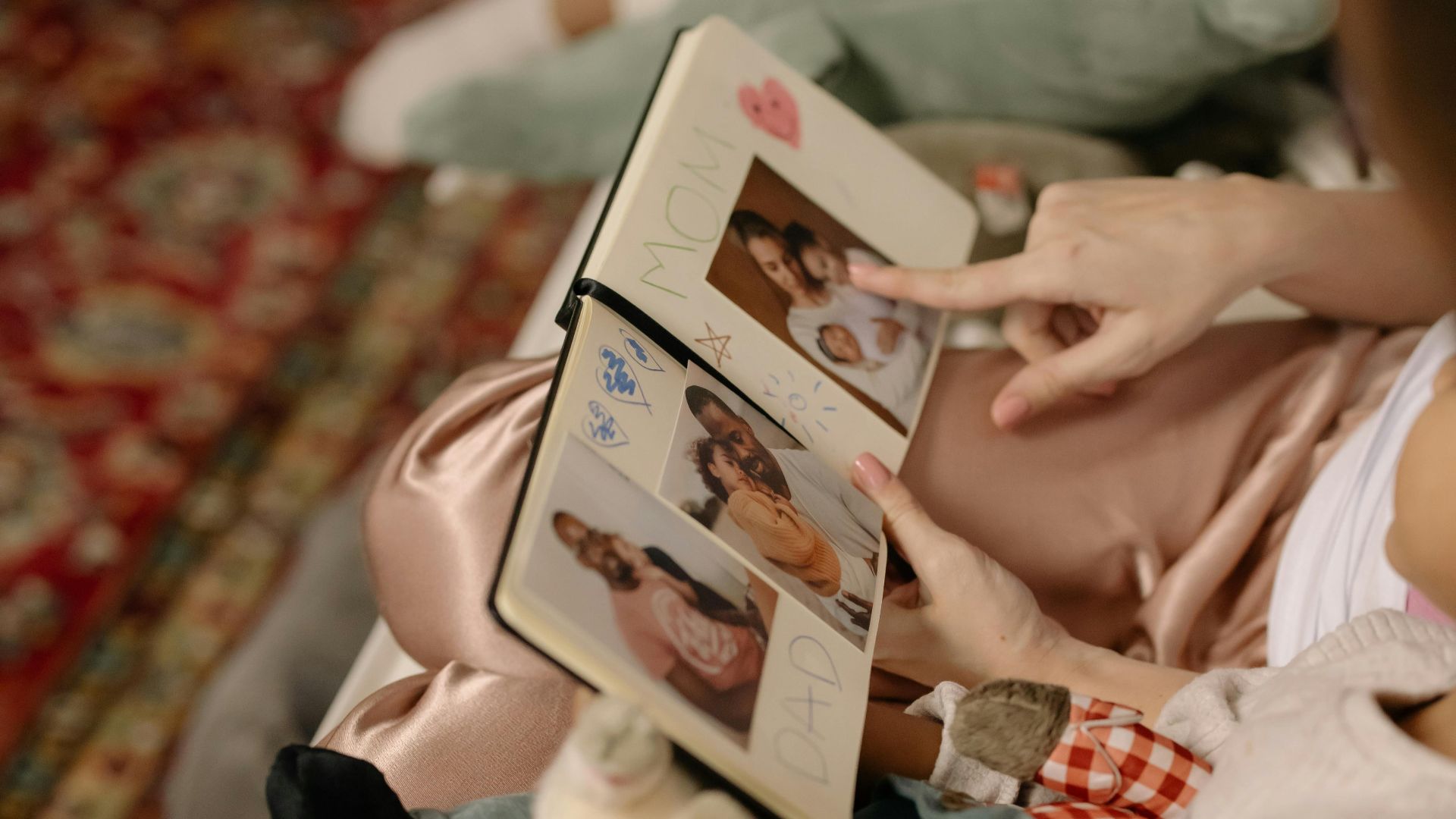 A child and parent bonding over a family photo album indoors.