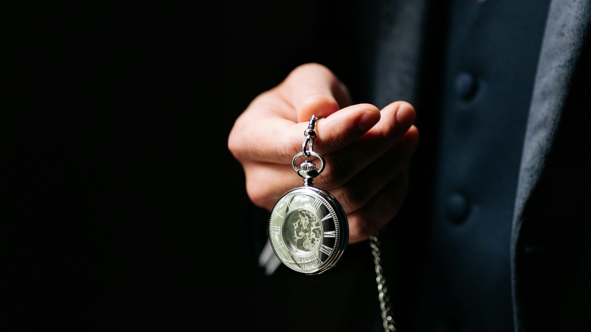 A gentleman in a suit holds a classic pocket watch, conveying timeless elegance and style.