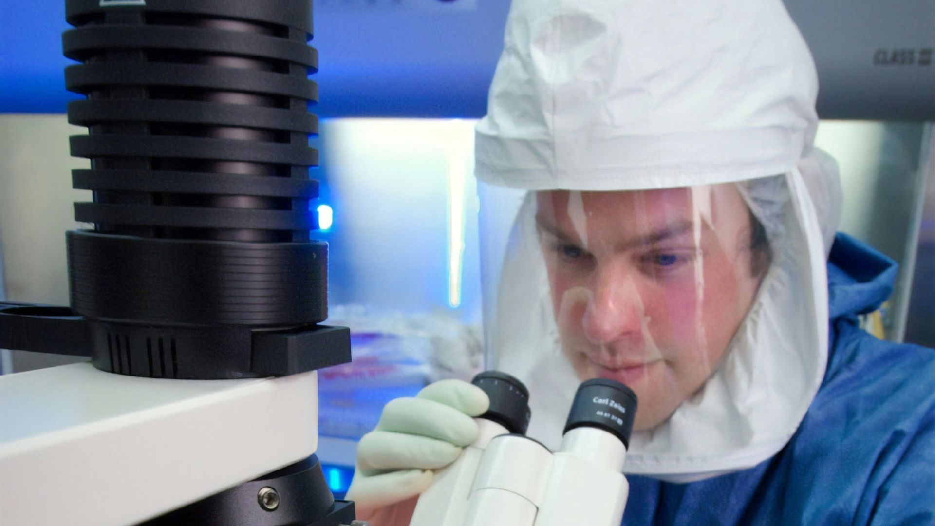 a woman in a lab coat looking through a microscope