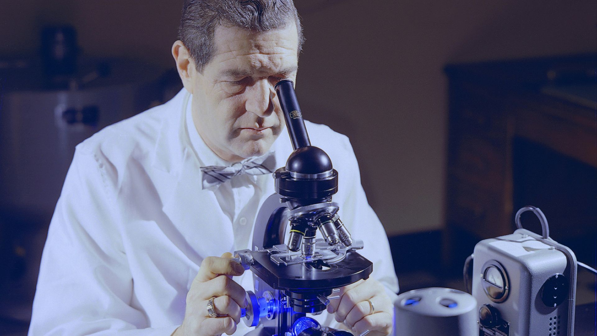 a man looking through a microscope at something