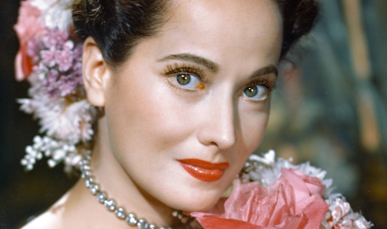 Merle Oberon poses with a bouquet of flowers in 1940.