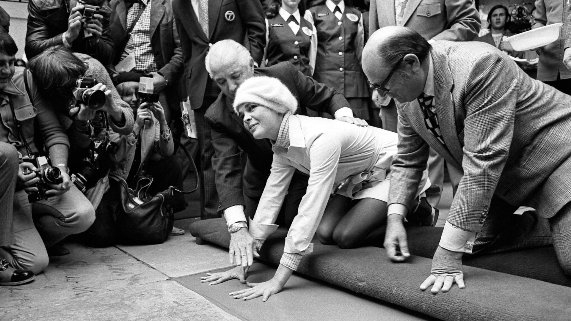 Actress Ali MacGraw placing her hand prints in cement at Chinese Theater in Hollywood