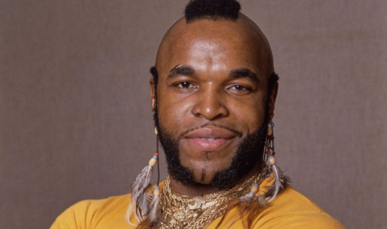 American actor Mr T, wearing a yellow t-shirt (with 'Rocky, The Italian Stallion' printed on the chest), with necklaces and feather earrings, during a studio portrait session, United States, circa 1982. Mr T appeared as Clubber Lang in 'Rocky III', released in 1982.