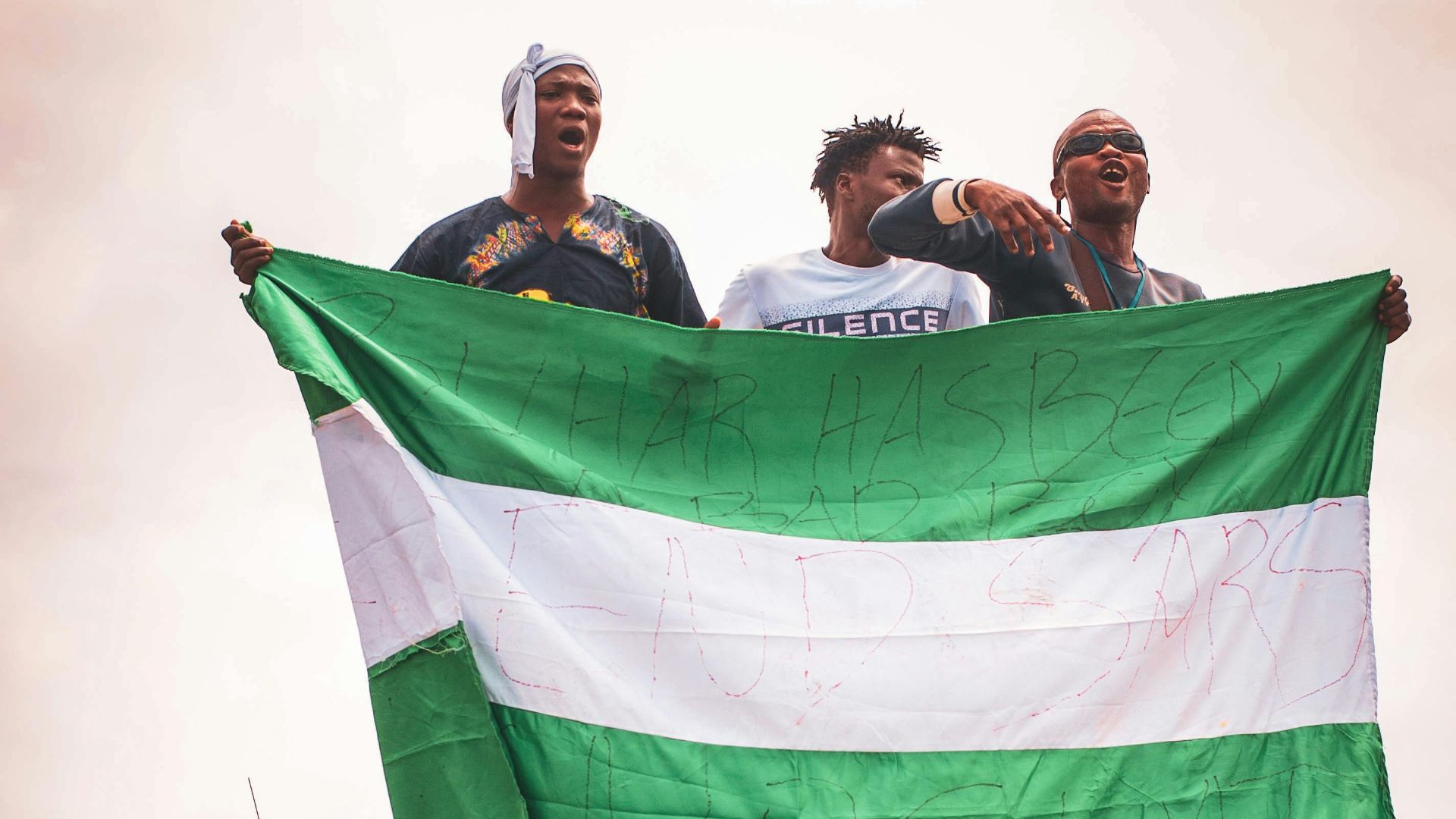 A group of men on a truck holding the Nigerian flag during a protest.
