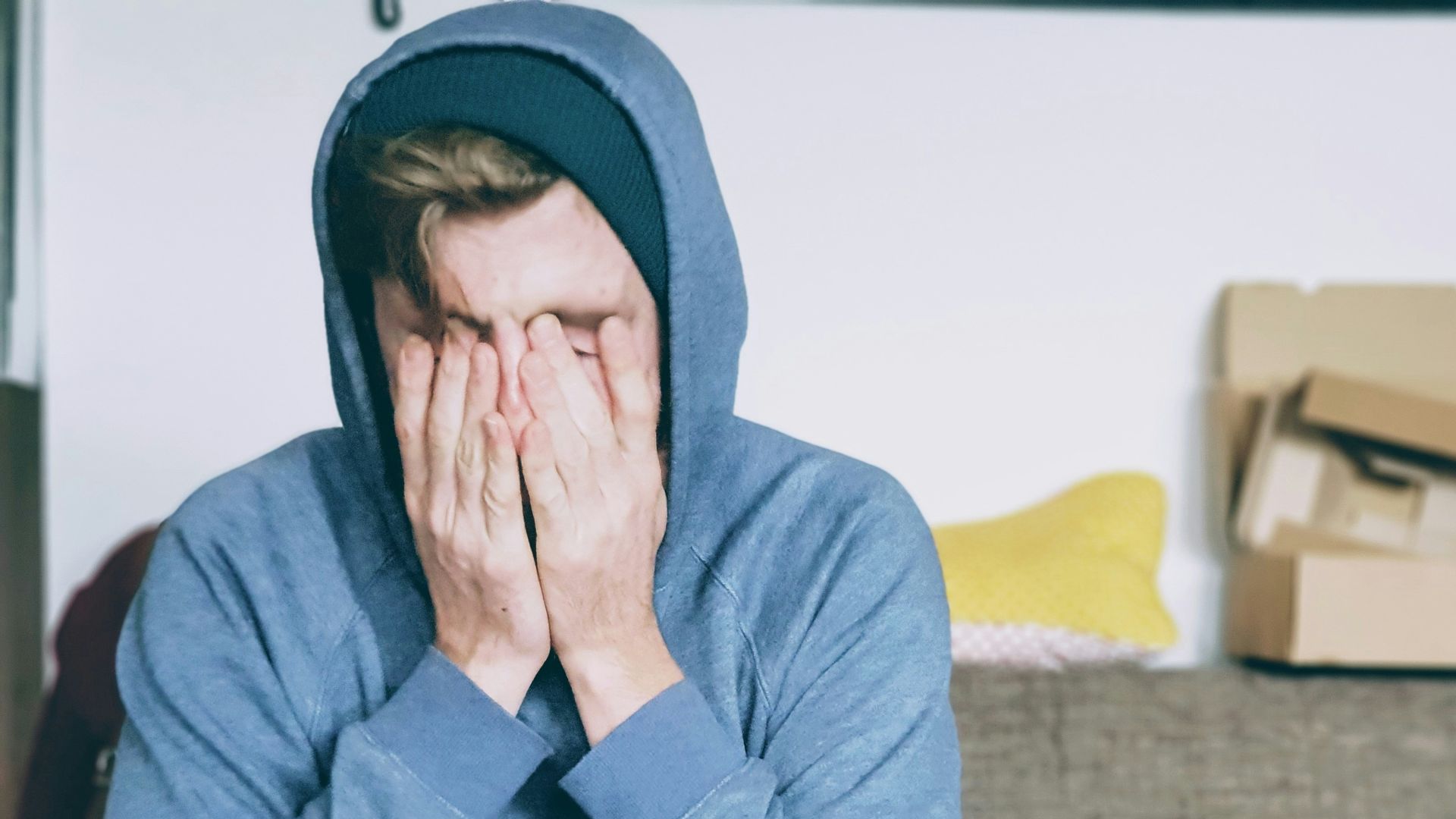 man covering face with both hands while sitting on bench