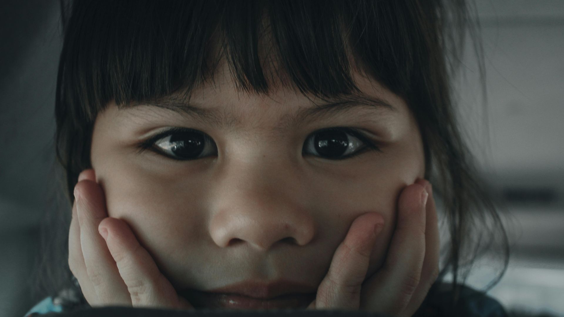 Close-up portrait of a cute child with a thoughtful expression indoors.