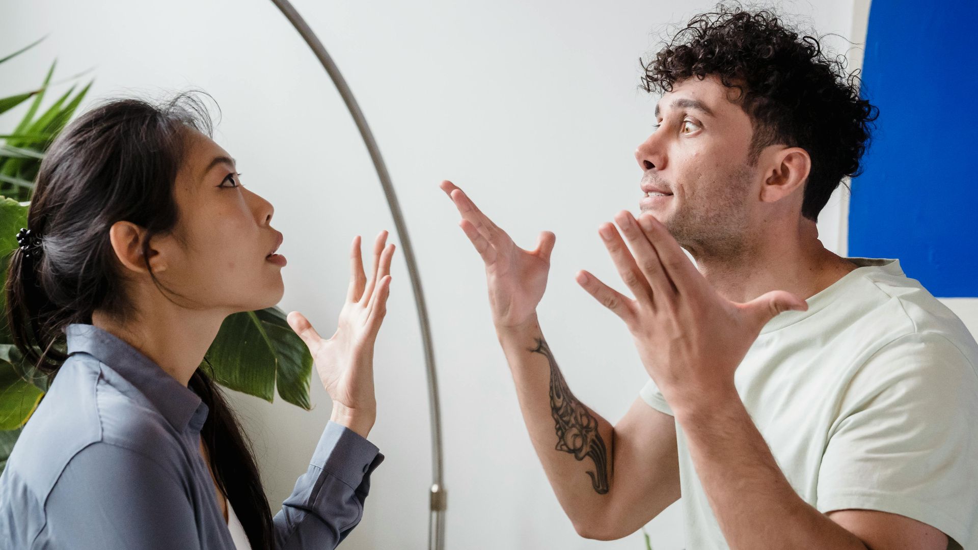 A couple argues indoors amidst greenery, showcasing emotions and interpersonal conflict.