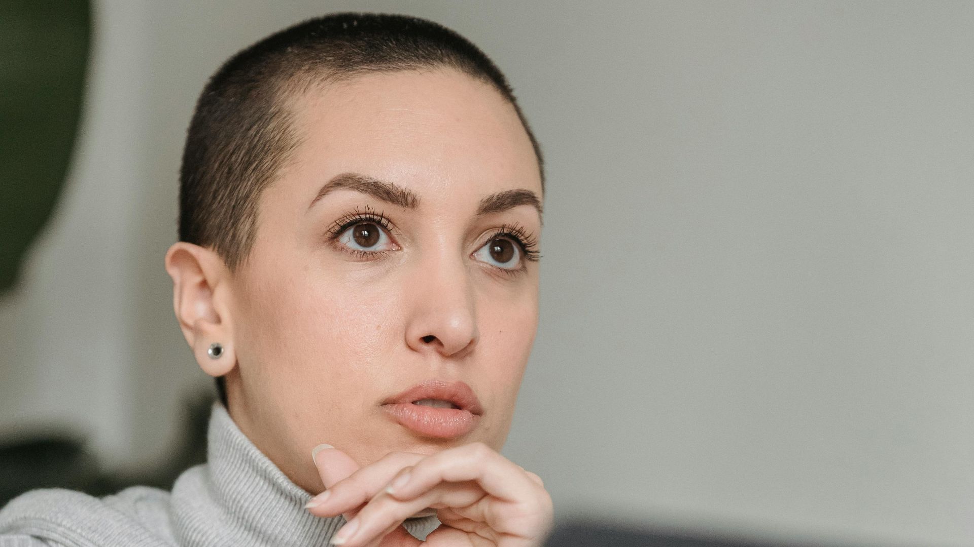 Crop female with dark short hair in casual clothes thinking near laptop and looking away