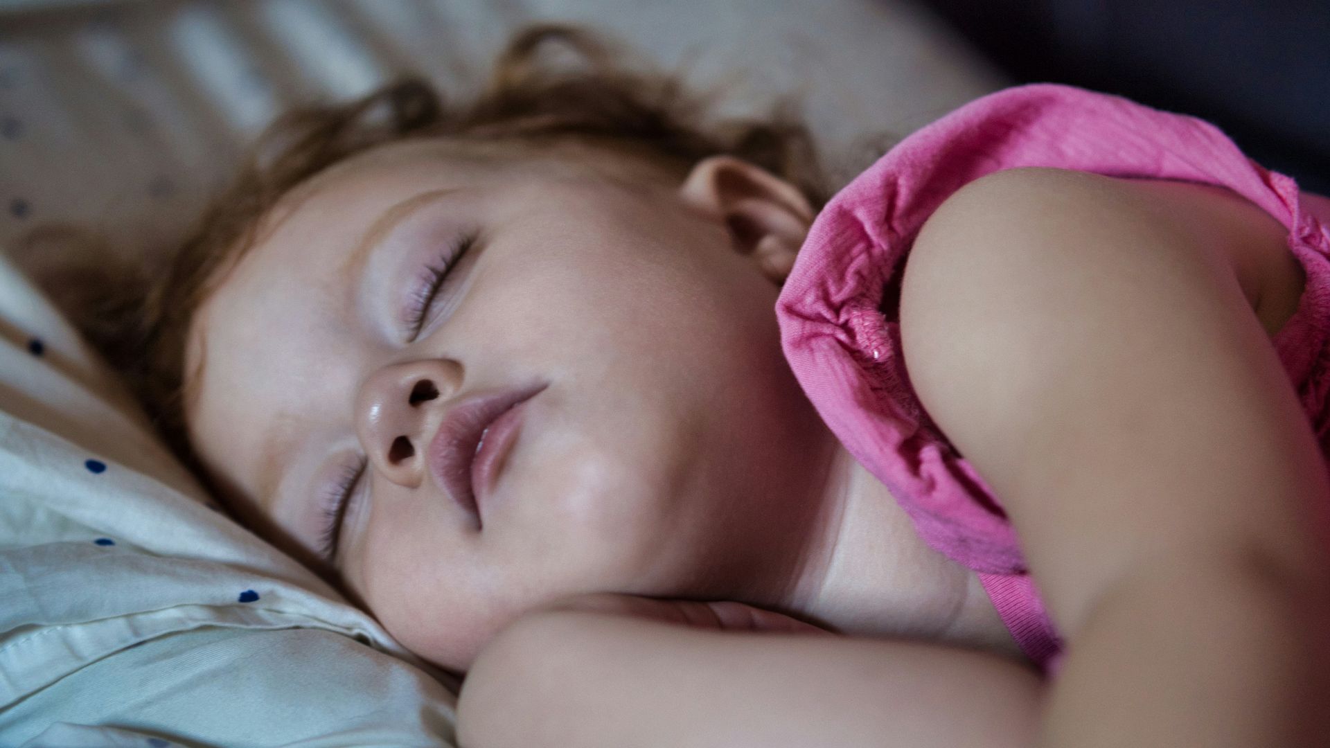 a little girl sleeping on a bed with her eyes closed