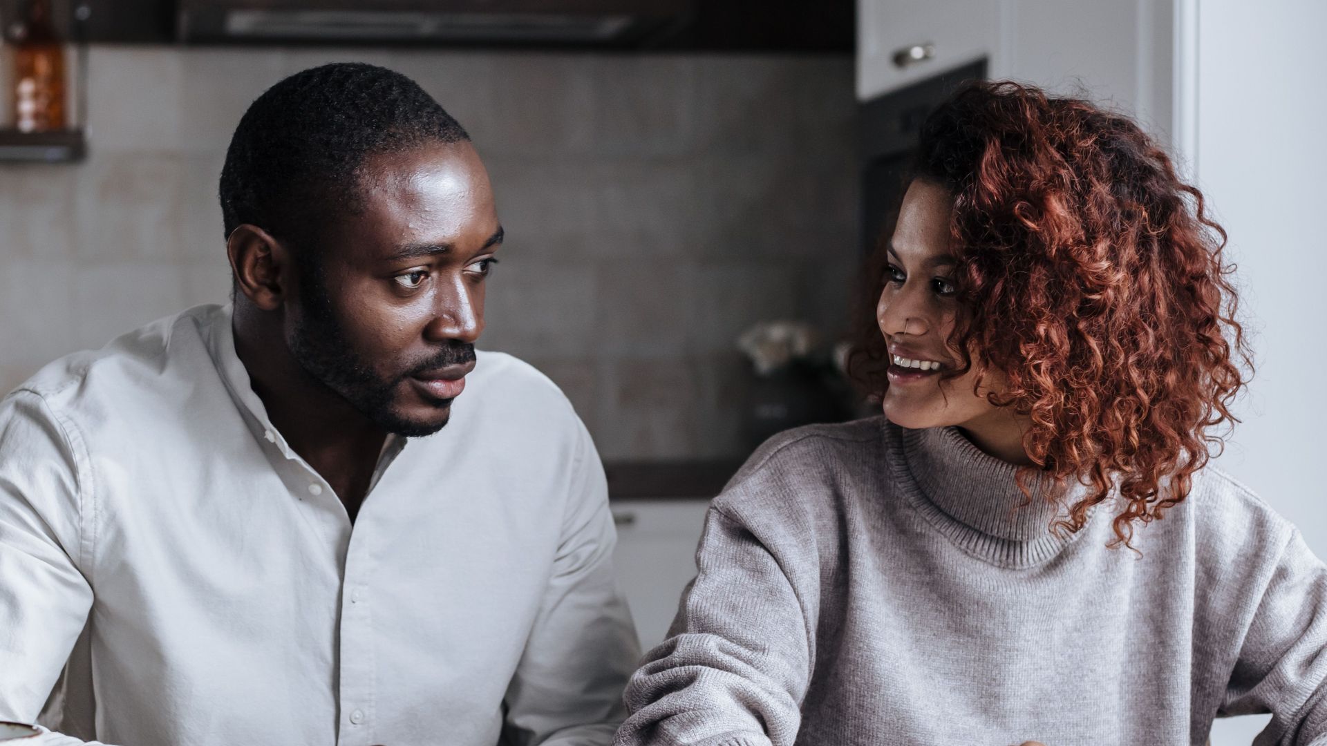 Black couple collaborating on a project at their kitchen table, showcasing teamwork and home office lifestyle.