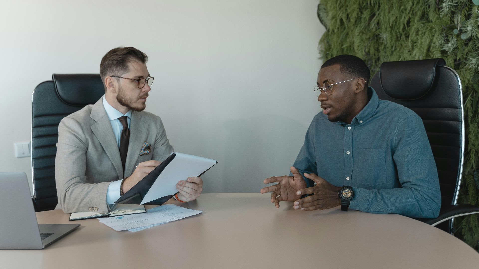 Two businessmen engaged in a discussion during a job interview in a contemporary office environment.