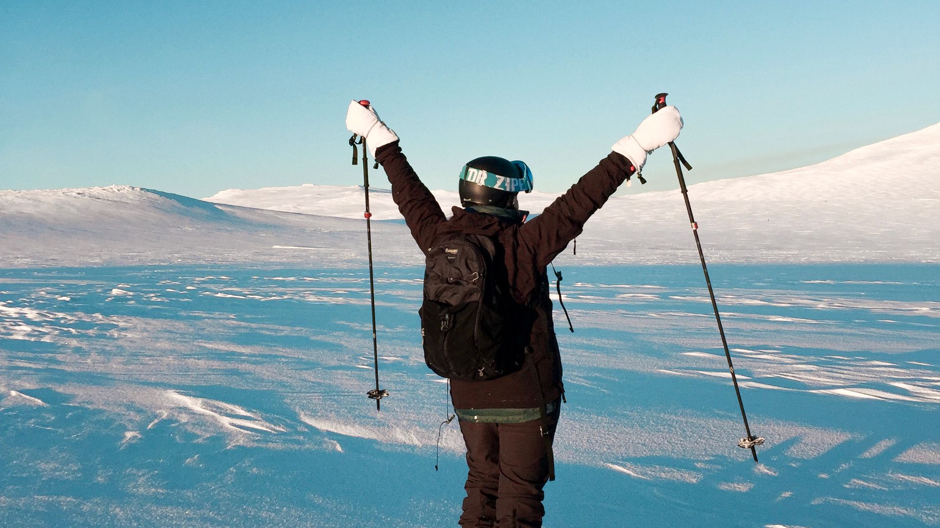 A skier celebrates amidst the vast, snowy terrain of Norway, capturing the essence of winter adventure.