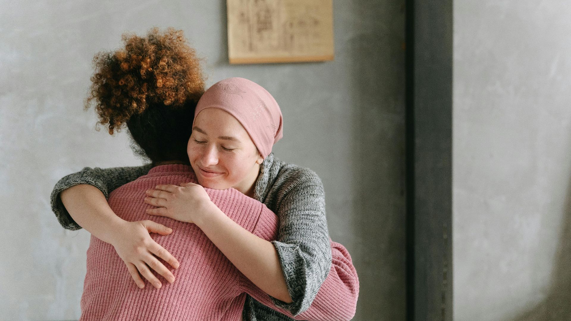 Two women embracing each other with warmth and love, symbolizing support and care indoors.