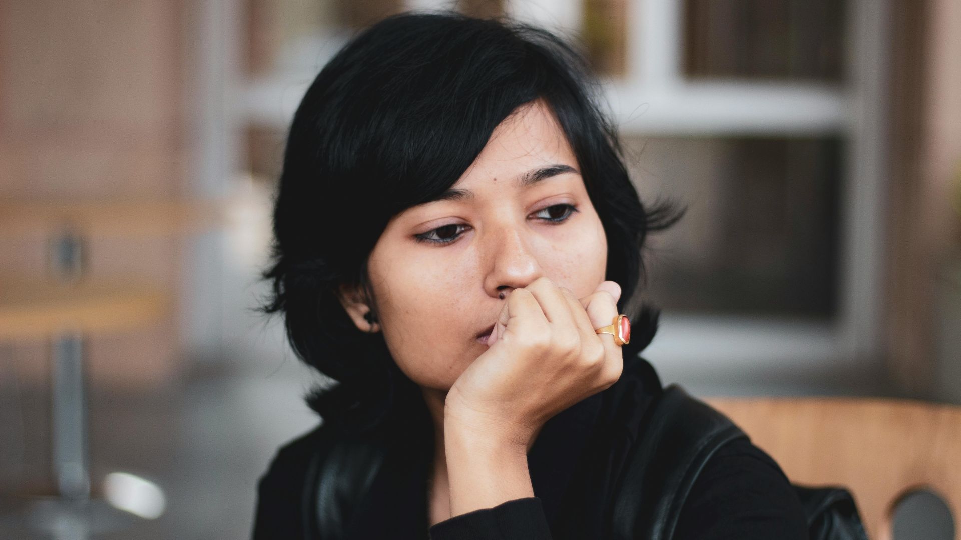 Portrait of a thoughtful woman indoors, lost in contemplation.