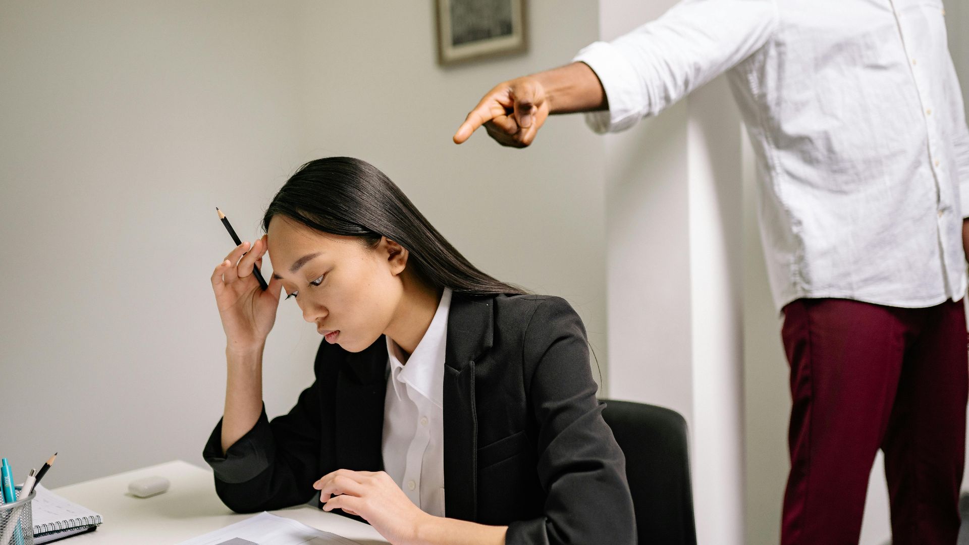 An office scenario depicting a young woman experiencing bullying from a coworker.