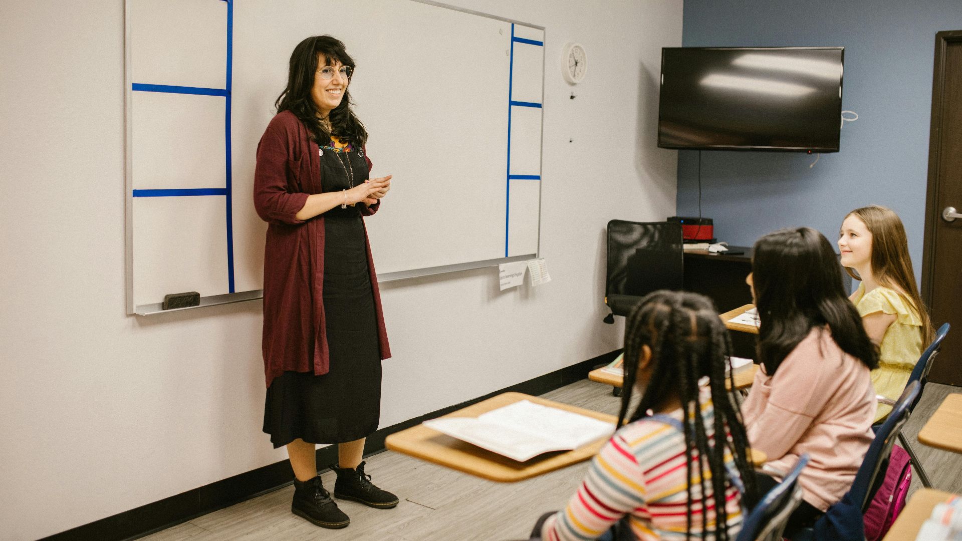 A teacher conducts a lesson with attentive diverse students in a modern classroom setting.