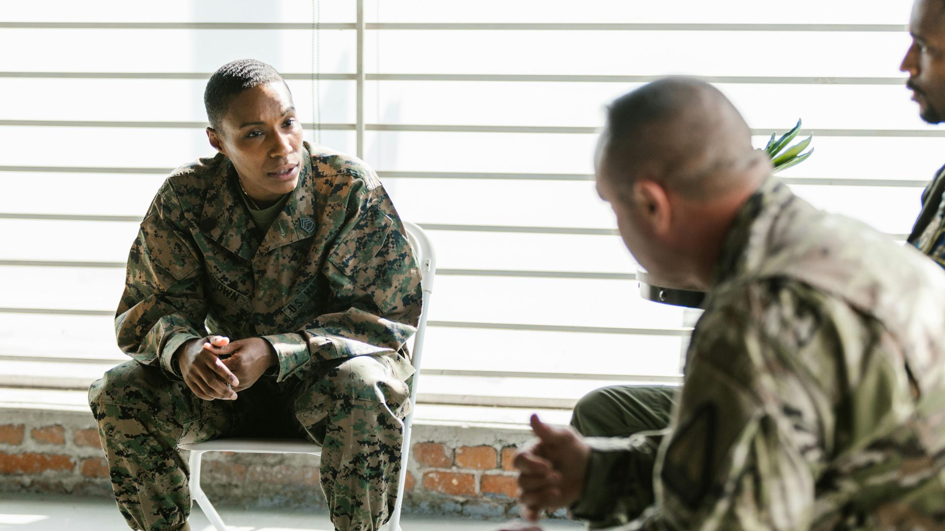 Military veterans engage in a supportive group therapy session indoors.