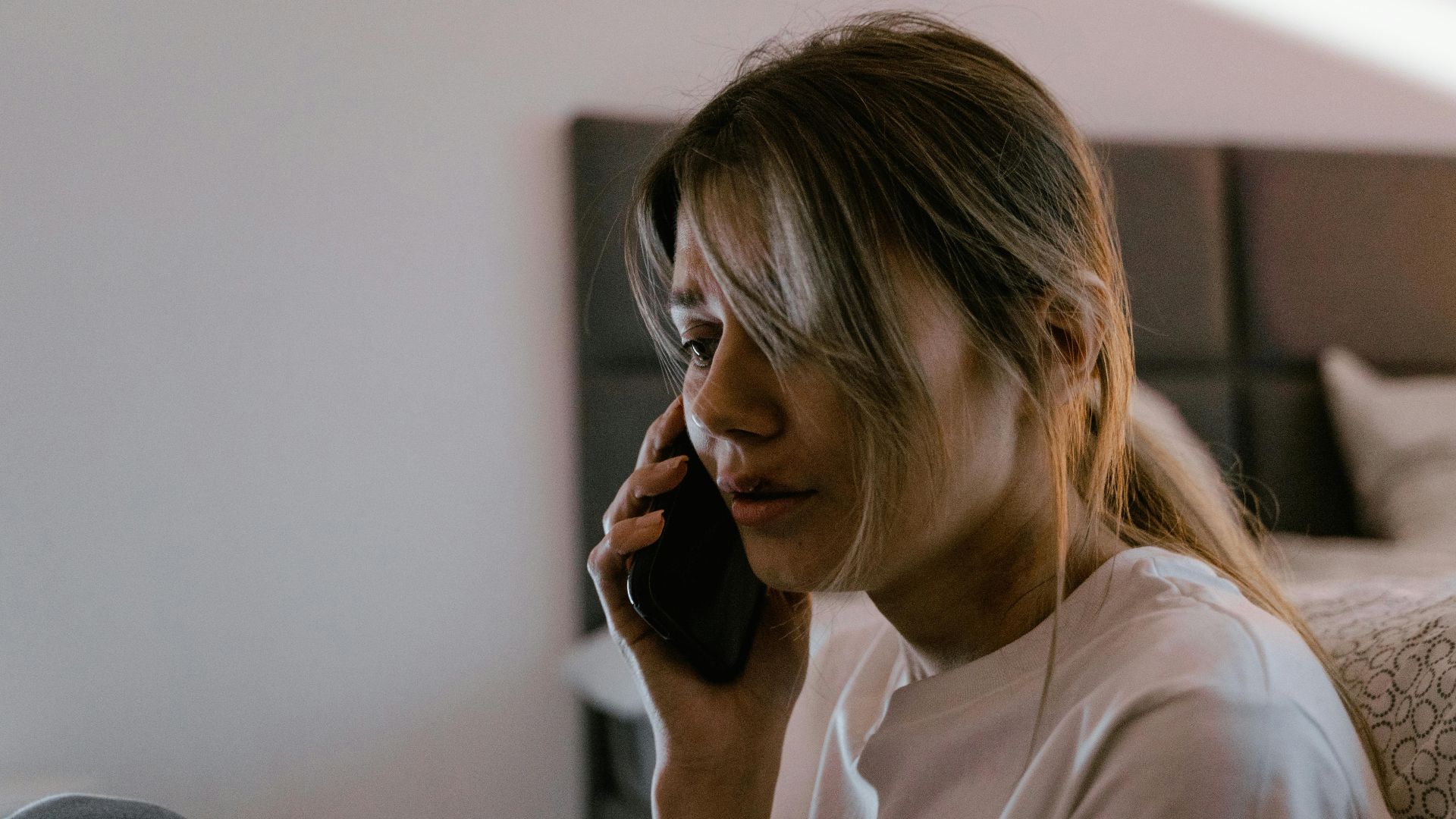 A worried woman on a phone call indoors, conveying stress and emotion.