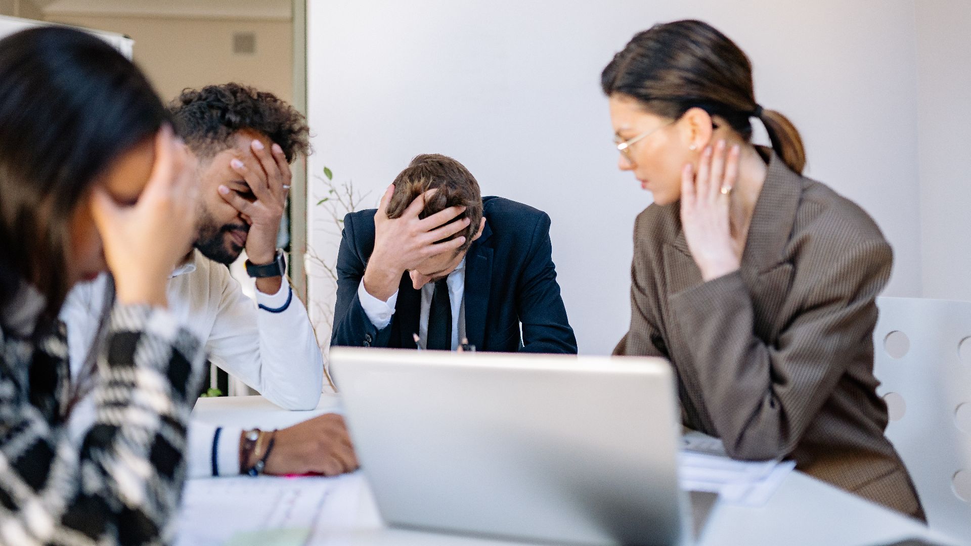 A group of stressed business professionals in an office setting, overwhelmed by work.