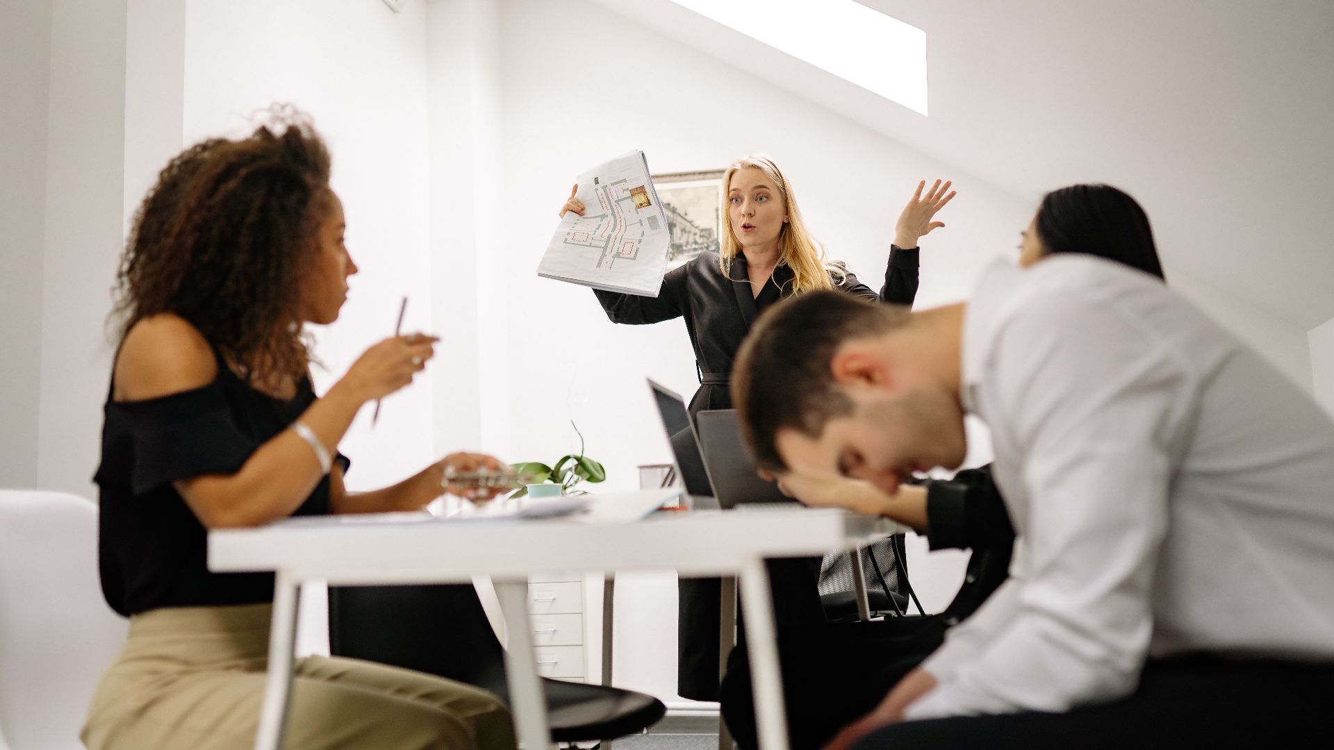 Team experiencing stress during a heated office meeting. Diverse colleagues engage in emotional discussion indoors.