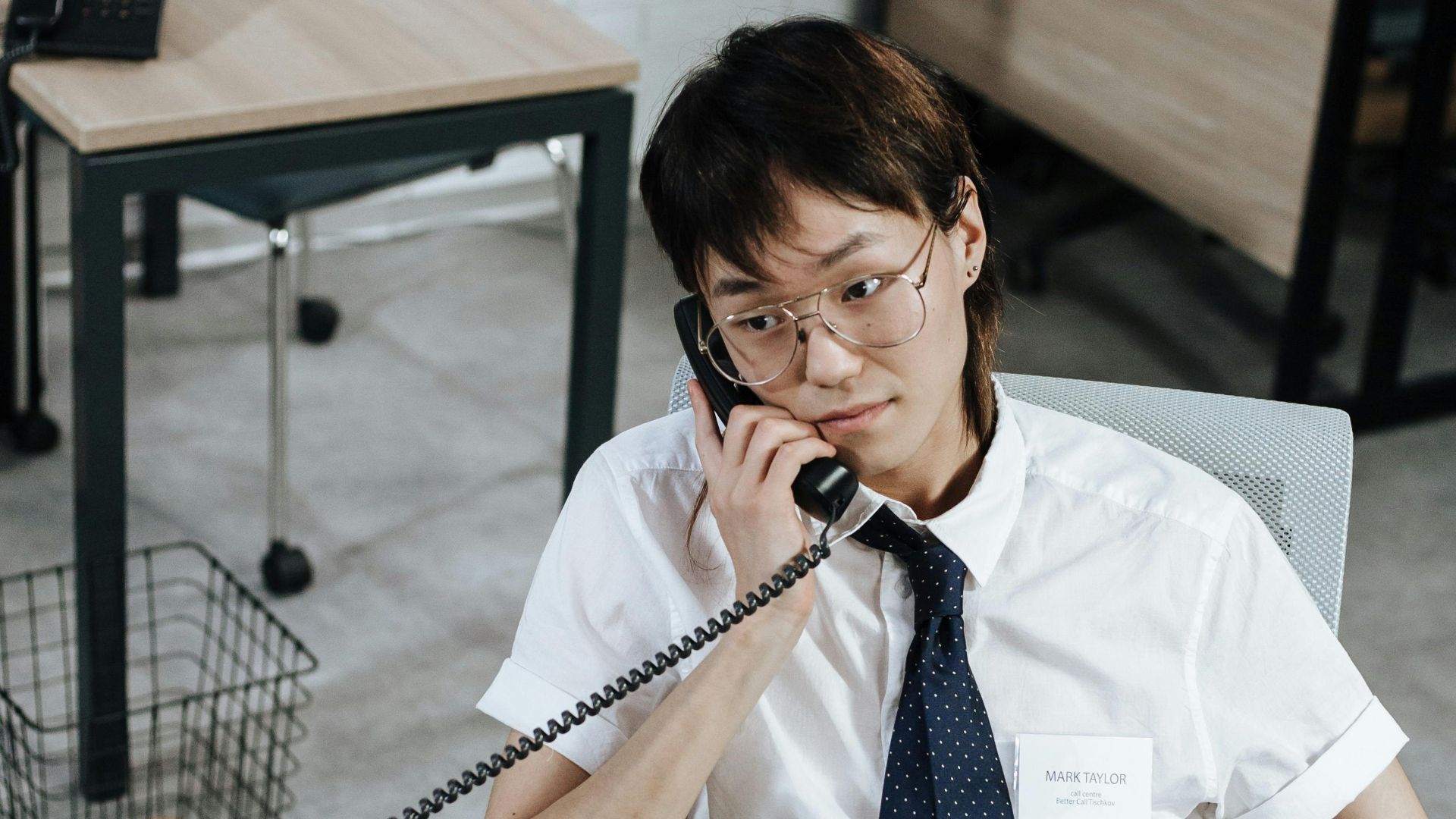 A focused customer service agent answering a phone call in an office setting.