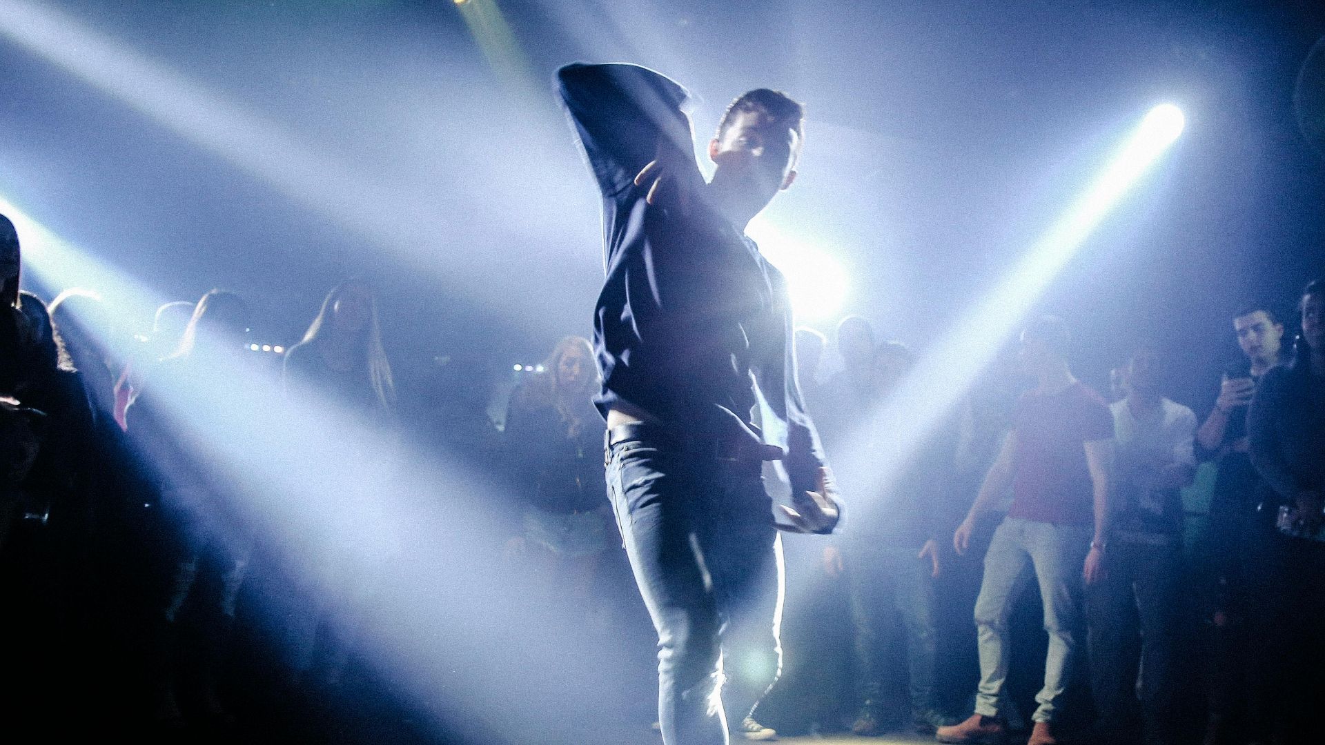 Energetic dance performance in a packed nightclub with vivid lighting effects.