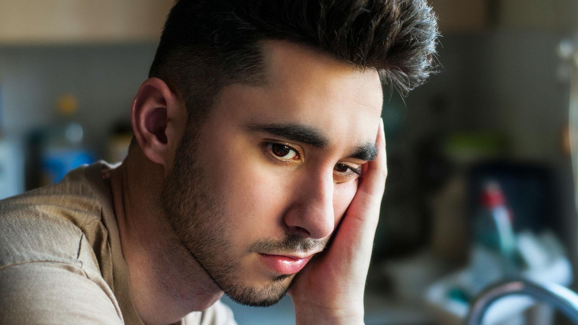 Portrait of a thoughtful young man in casual wear, indoors with soft lighting.