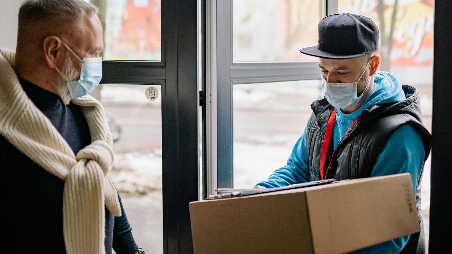 Masked delivery service during pandemic, showcasing contact-free parcel handover.