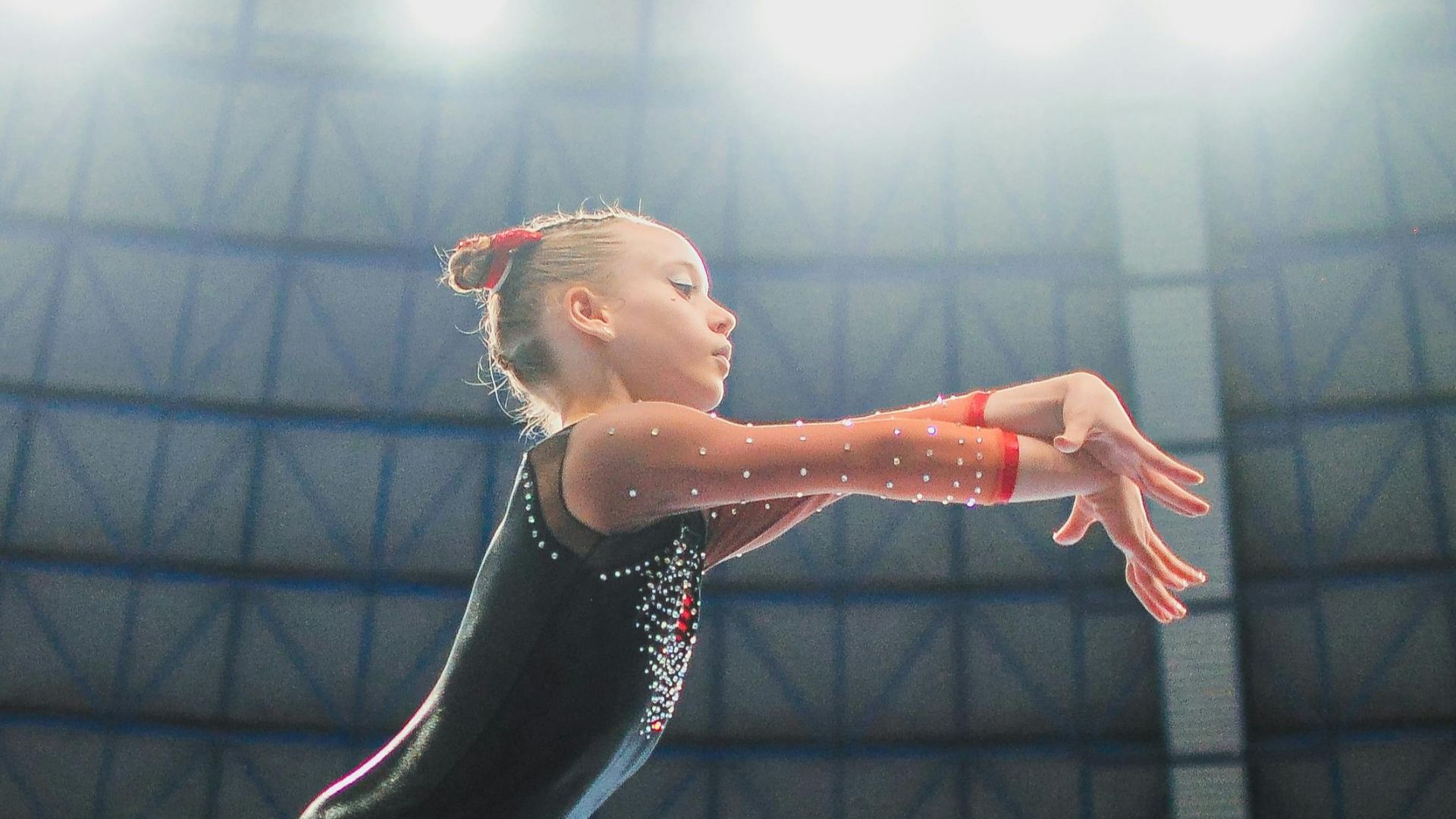 A young gymnast performing a routine on the balance beam indoors during a competition.