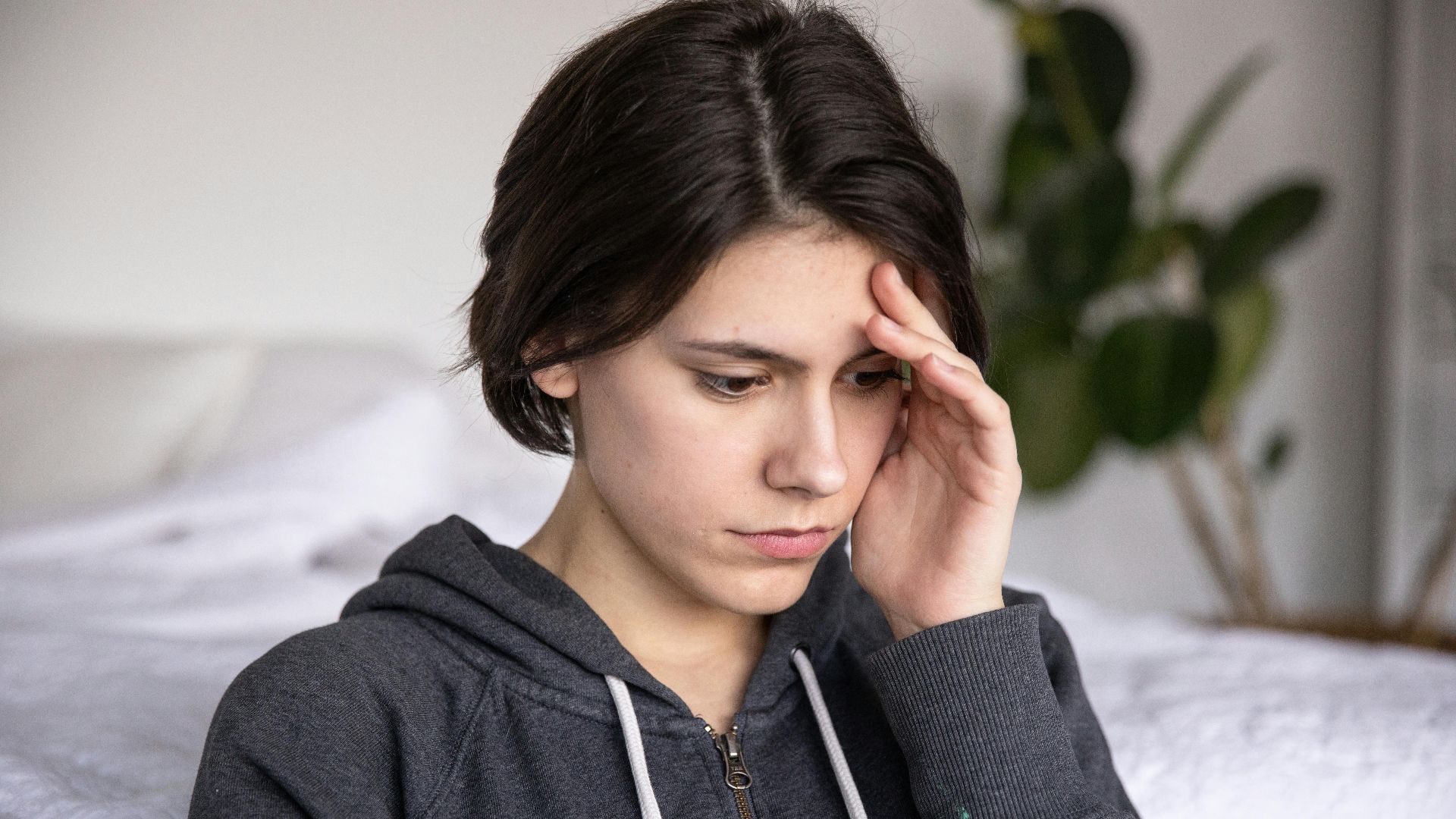 Young woman in a hoodie appearing thoughtful and pensive, captured indoors.