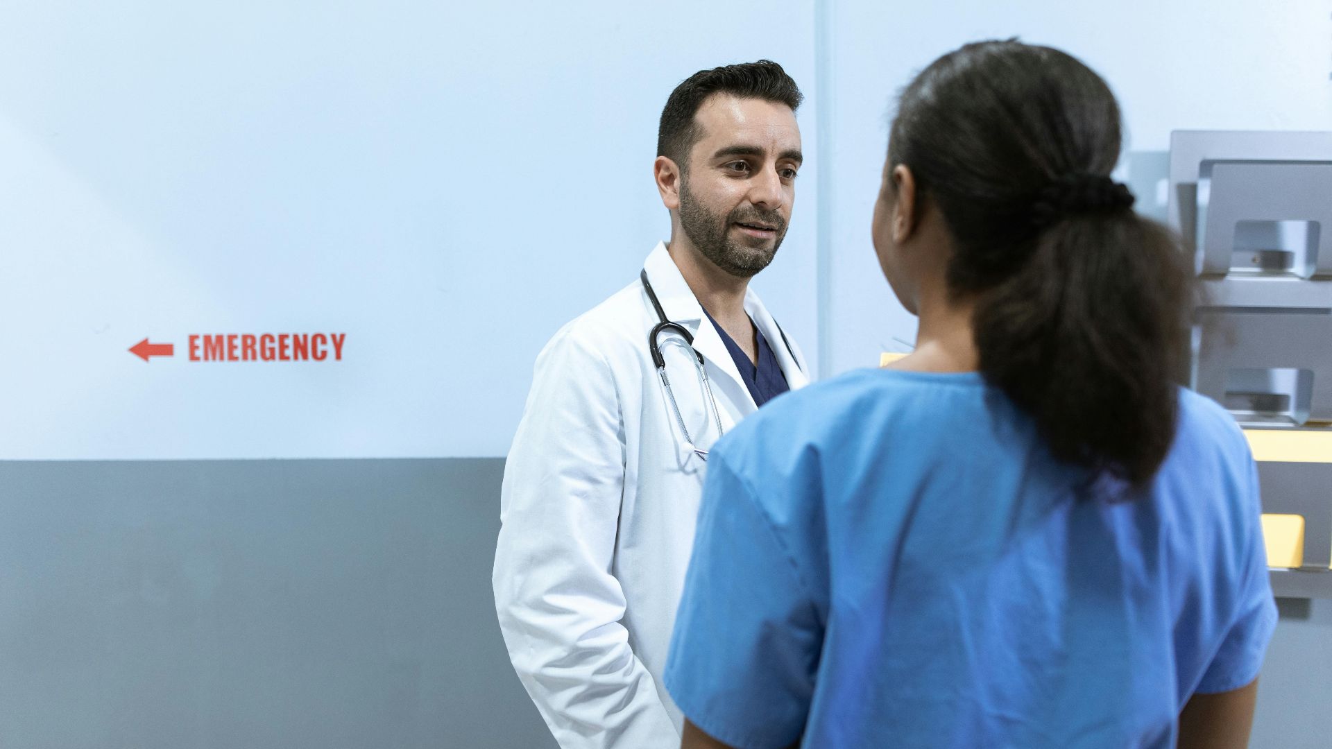 Doctors and nurses conversing near emergency room in a hospital setting.