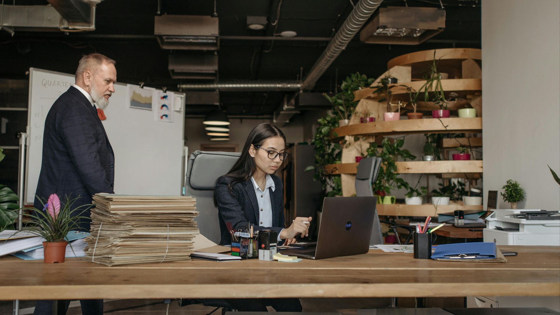 Business team in an office working together with modern equipment, plants, and documents.