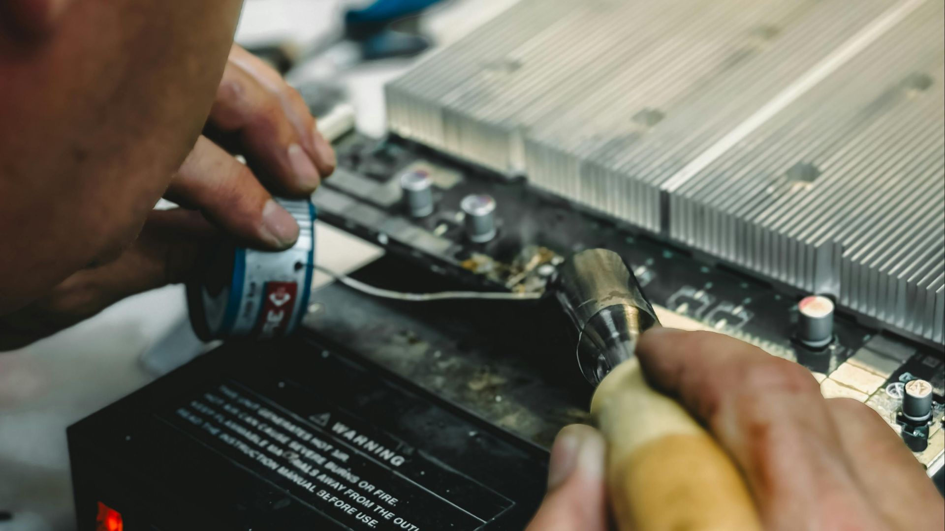 Technician using soldering iron on a circuit board, showcasing precision work in electronics repair.