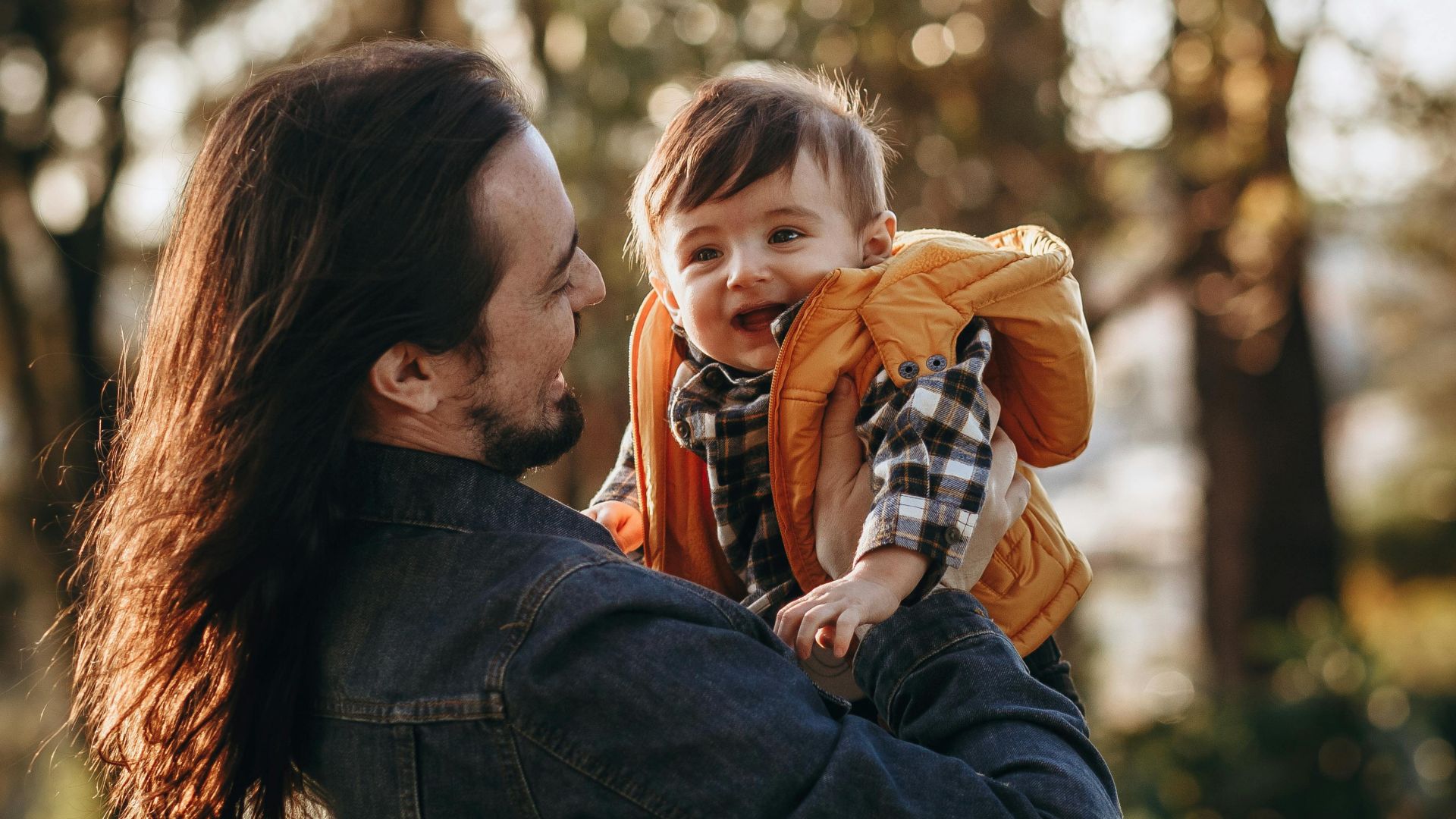 A joyful moment between father and child in an autumn park with warm natural light.