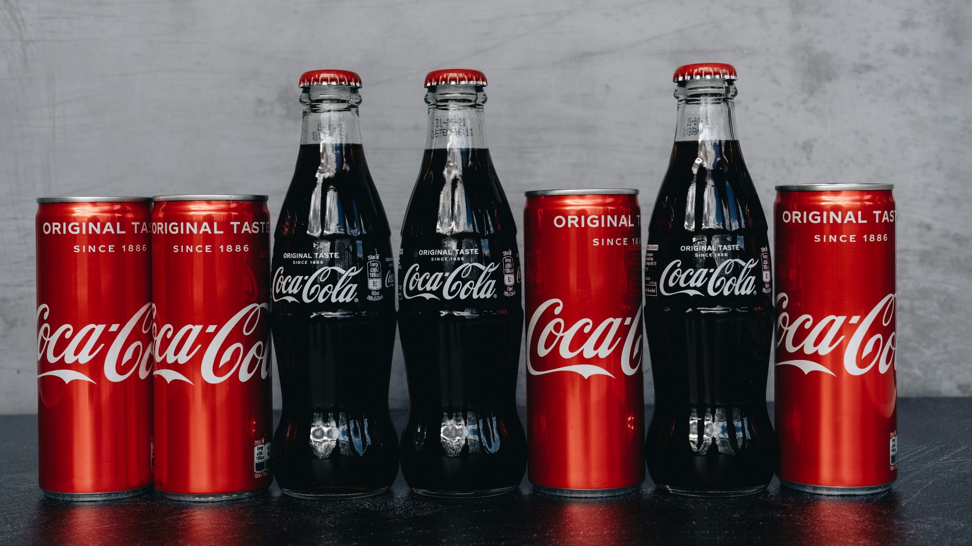 A lineup of Coca Cola bottles and cans representing the classic and refreshing brand image.
