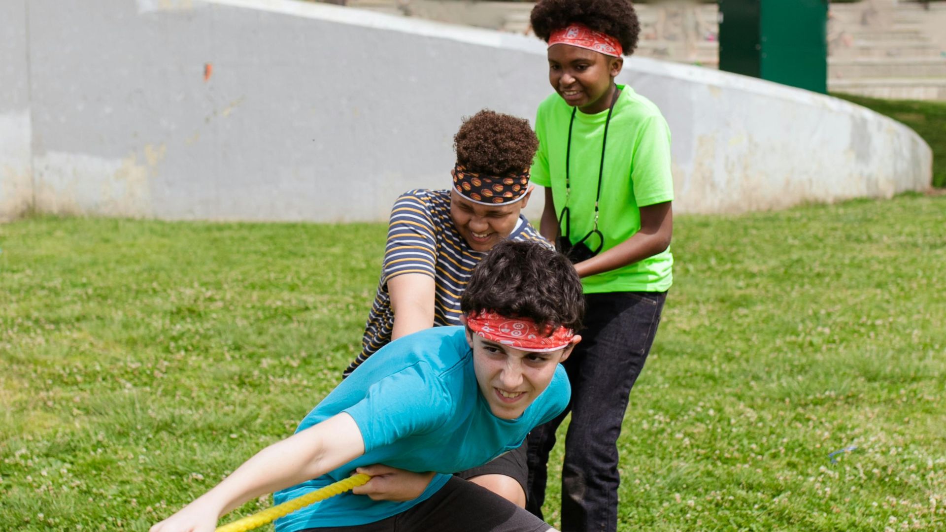 Group of children enjoying a tug of war game outdoors on a grassy field.