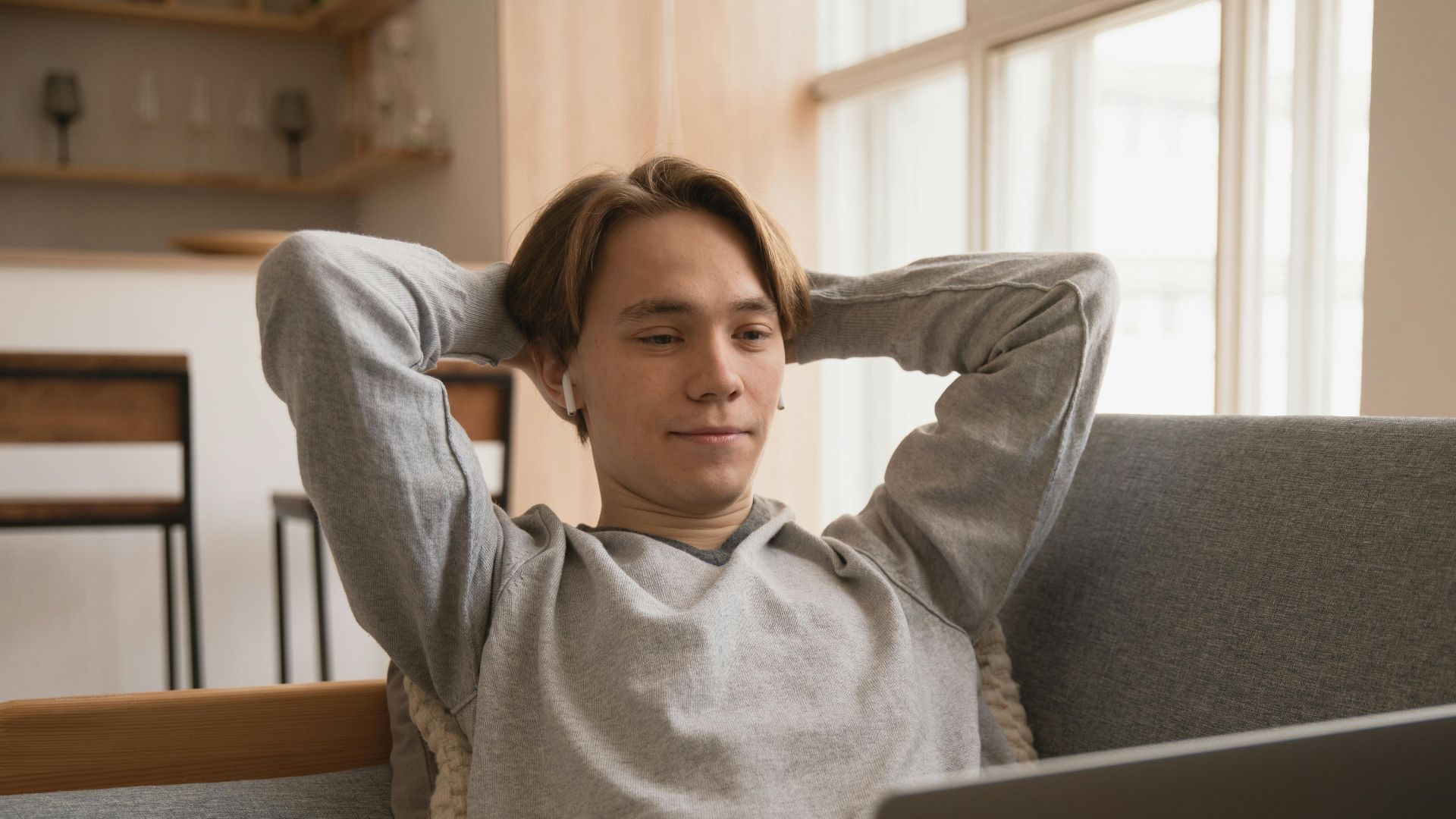 Young man leisurely using a laptop at home, exuding a relaxed atmosphere.